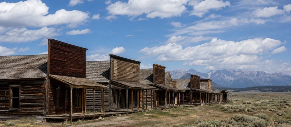 Preserved nineteenth-century timber frontier buildings under a wide Wyoming sky