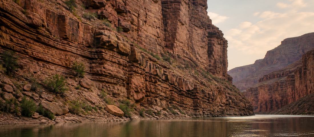 A river gorge with steep red rock walls and calm water below