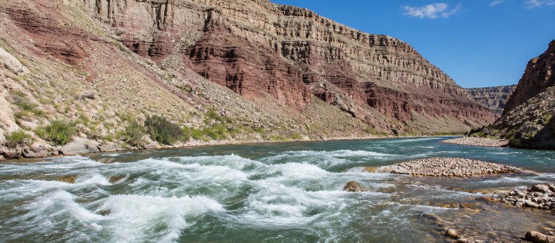A whitewater river running through a banded rock canyon in Wyoming