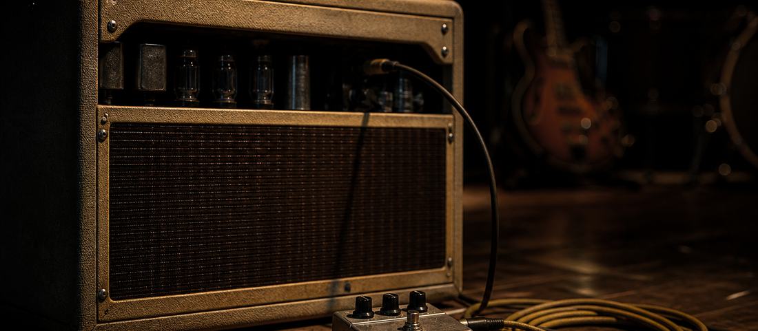 A valve guitar amplifier and a delay pedal on a darkened stage floor